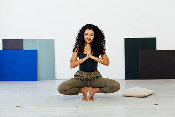 woman doing exercises yoga asana in white gym