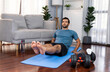 © InfiniteFlow - Athletic and sporty man doing crunch on fitness mat during home body workout exercise session for fit physique and healthy sport lifestyle at home. Gaiety home exercise workout training concept.