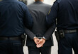 © Hanna - Police officers arrest a man in a suit while handcuffed on a city street during the day