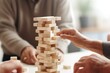 © Archil - Close-up of diverse seniors gathered around a game of Jenga, sharing laughter and connection, emphasizing community and joy.