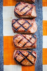 Canvas Print - Five perfectly grilled pork chops in a row on a checkered tablecloth.