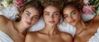 © Wall - Three young women recline on a bed, adorned with flowers in their hair