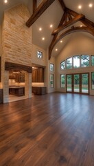 Wall Mural - Spacious living room with vaulted ceilings, exposed beams, a stone fireplace, hardwood floors, and large windows.