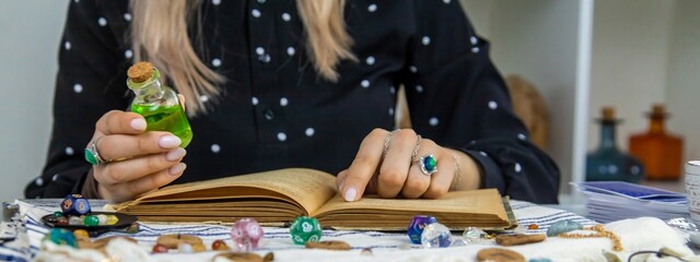 Woman fortune teller reads a book of spells. Selective focus.