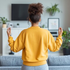 Poster - Woman in yellow sweatshirt meditating in living room.