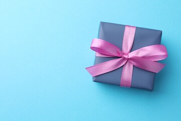 Wall Mural - Gift box with bow on light blue background, top view. Space for text