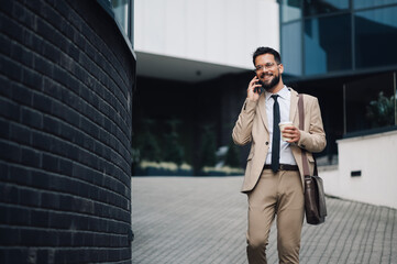 Businessman walking and talking on phone outside office building