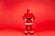 © khosrork - Full length backside portrait of elderly man with gray beard wearing santa claus costume standing with hands on hips, looking at something.