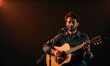 © Ruslan Gilmanshin - man performing on stage, playing an acoustic guitar and singing into a microphone. The lighting is warm and focused on the performer, creating an intimate and calm atmosphere
