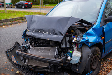 heavily damaged car with crumpled hood and exposed engine, aftermath collision, crash scene, with visible damage to front end