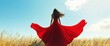 © DIAHIMAGESNEW - Woman in red dress with flowing fabric in field.
