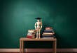 © joeycheung - A wooden figurine wearing a graduation cap stands atop a stack of books on a wooden table in front of a chalkboard.