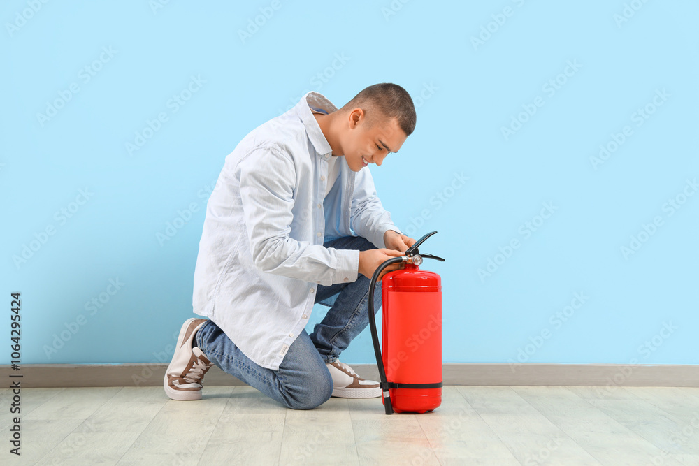 Teenage boy with fire extinguisher near blue wall