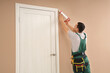 © Pixel-Shot - Male worker with caulking gun sealing cracks between door and wall at home