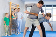 © JackF - Concentrated man with trainer in sport club during self-defense training, sparring and practicing technique of hand grab