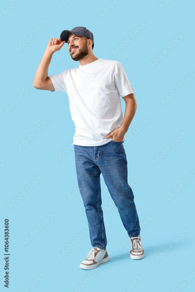 Young man in cap and white t-shirt on blue background