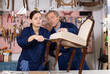© JackF - Young woman apprentice learning from skilled old repair specialist restoring Victorian chair during workday in furniture workshop