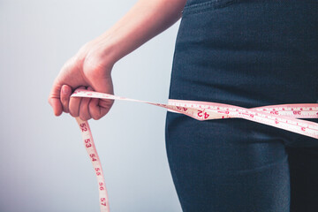 Wall Mural - woman measuring her waist with tape on the white background