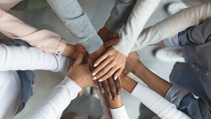 Wall Mural - Close up of international business team showing unity with putting their hands together on top of each other. Concept of teamwork, top view