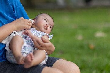 Loving mother with her newborn baby on her arms at outdoor park during evening