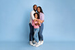 © Prostock-studio - Happy Loving Family. Vertical full body length shot of African American woman and man embracing smiling girl standing isolated on blue studio wall. Cheerful mother and father posing with daughter