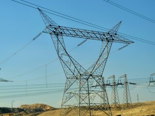 A transmission tower, electricity pylon which is a tall steel lattice structure that used to support overhead high voltage power lines, high voltage electric pillar and sky background in Egypt