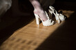 © Vasil - A pair of white high heels are laying on a wooden floor. The shoes are closed and the woman's feet are not visible. The image has a calm and serene mood, as the shoes are not being worn