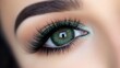 © Elmin - A close-up view of a woman's green eye, enhanced with long, layered false eyelashes. Her eye makeup is flawless, highlighting the beautiful shape of her eyes.