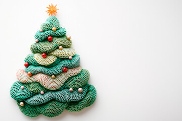 A cute Christmas tree, knitted with yarn, on a white background. Flat lay, top view, with copy space for text