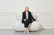 © boomeart - Confident businesswoman in pantsuit sits on bean bag
