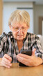 © StockMediaSeller - Senior woman frowning at her smartphone, appearing confused or frustrated while using the device indoors.
