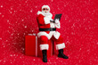 © deagreez - Full length photo of grandfather white beard sit package hold netbook amazed receive lot e-mails wear x-mas santa costume glove coat belt sunglass cap boot isolated red color background