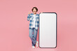 © ViDi Studio - Full body young woman wear blue shirt white t-shirt casual clothes big huge blank screen mobile cell phone smartphone with area point index finger up isolated on plain pastel light pink background.