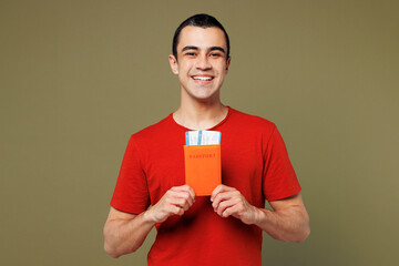 Traveler smiling fun man wear red casual clothes hold passport ticket isolated on plain green color background. Tourist travel abroad in free spare time rest getaway. Air flight trip journey concept.