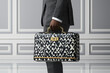 © zamuruev - A well-dressed professional carries a geometric briefcase, exuding confidence in a modern office environment
