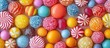 © MBRAMO - A close-up shot of a variety of colorful candies and sweets, including hard candy, gum, and lollipops.  The candies are arranged in a random pattern on a pink background.