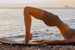 © Mirrorstudio - Young slim woman practicing yoga on beach