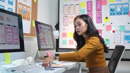 Wall Mural - female ux designer reviewing website design on a computer in a modern office setting, focusing on us