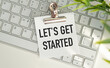 © Pawel - Let's Get Started- text written on sticky note lying on the keyboard with office background