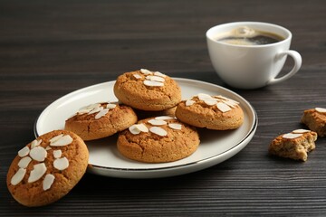 Tasty cookies with almond flakes and coffee on wooden table, closeup