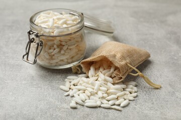 Wall Mural - Puffed rice in jar and sack on light grey table, closeup