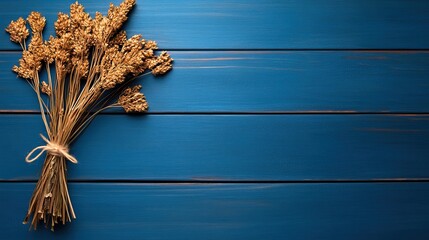 A rustic bouquet of dried flowers tied with twine rests on a blue wooden surface, creating a serene and natural aesthetic.