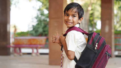 Portrait of happy indian teenager school boy with backpack holding books. Smiling young asian male kid looking at camera.