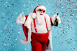 © deagreez - Photo of retired old man grey beard carefree hold bottle glass sparkling wine midnight club celebration confetti wear santa x-mas costume suspender sunglass cap isolated blue color background