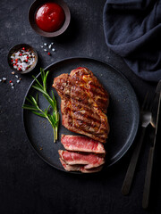 Wall Mural - Beef Steak medium rare with French fries on a black plate. Dark background. Top view.