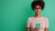 © Tiravad - Young woman with smartphone, green background