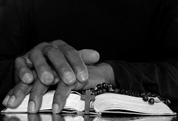 praying to god with hands together with cross crucifix and bible on grey black background with people stock photo stock image	