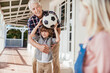 © Marko Geber - Grandfather and grandson playing with soccer ball on house porch