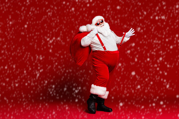 Wall Mural - Full length body size view of his he attractive childish cheerful cheery funny fat Santa carrying big large sack having fun dancing isolated bright vivid shine vibrant red color background