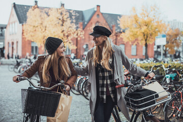 Wall Mural - Young women walking on a city street shopping and pushing a bicycle